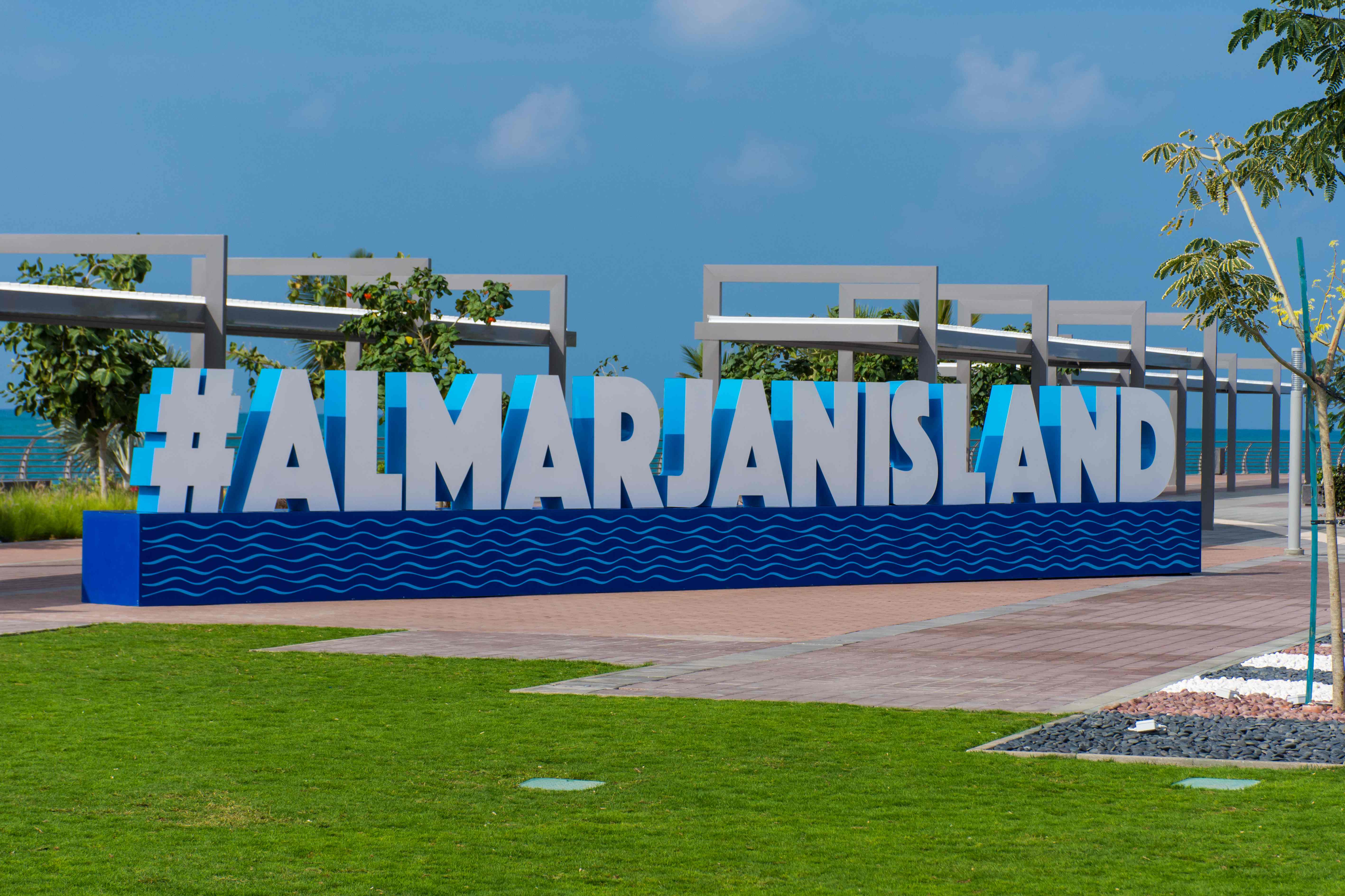 Iconic #ALMARJANISLAND landmark sign with blue wave pattern at entrance of Al Marjan Island tourist destination in Ras Al Khaimah UAE